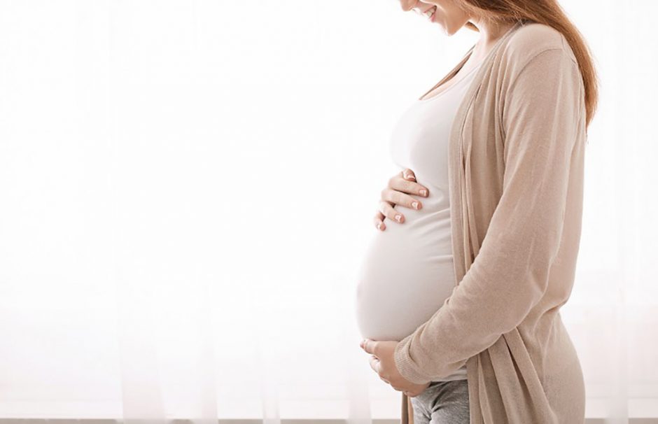 Beautiful pregnant woman hugging her tummy at home